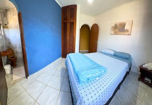 Une chambre à coucher comprenant un lit, une armoire en bois, une salle de bain avec des toilettes et un lavabo.