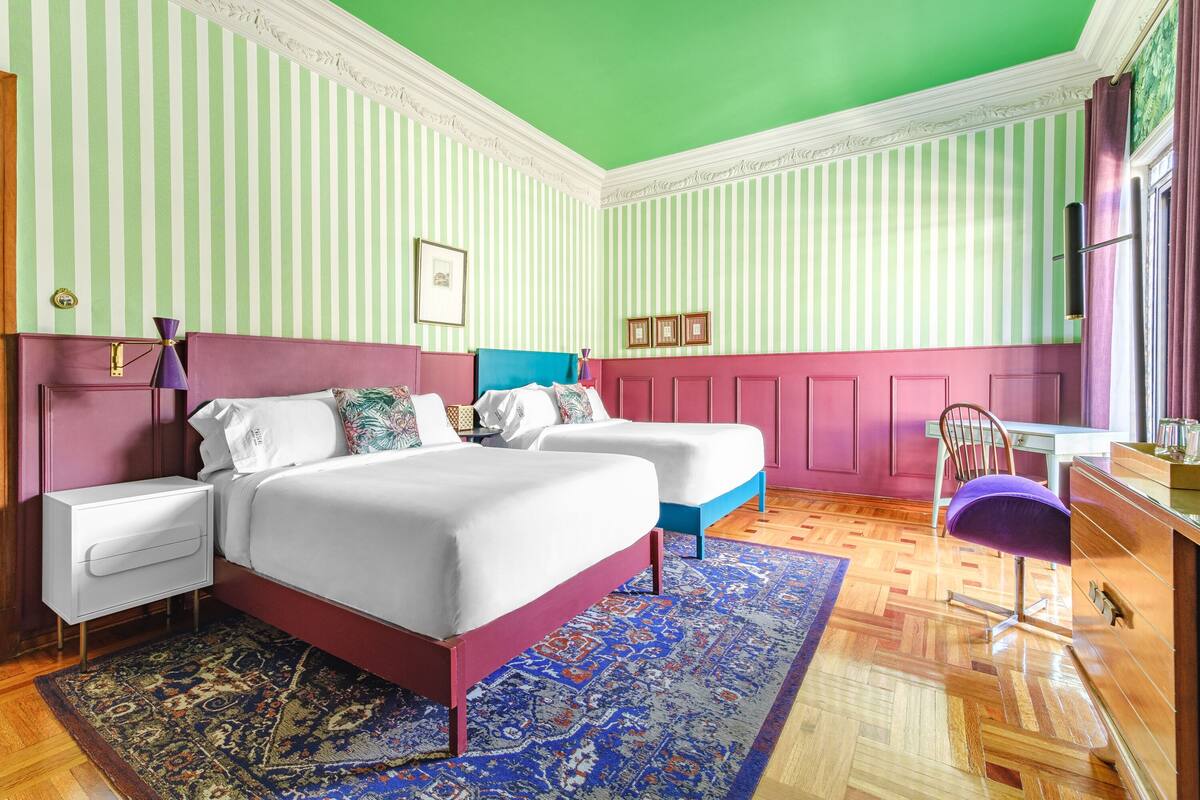 Une chambre avec un lit, deux tables de chevet, une chaise et un bureau.