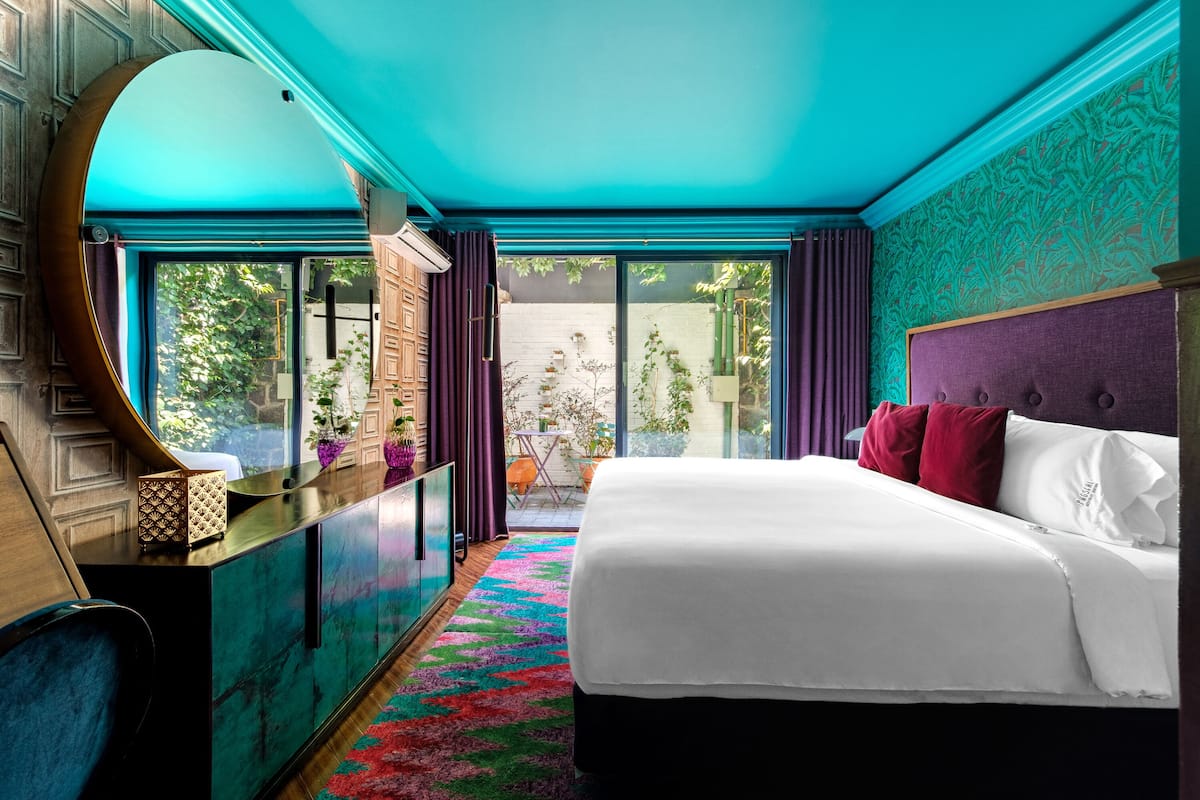 Une chambre d’hôtel moderne dotée d’un grand lit, offrant une vue sur le jardin et possédant un plafond incurvé original.