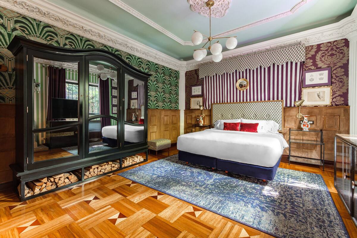 Une chambre à coucher avec un grand lit, un miroir, une commode et un téléviseur.