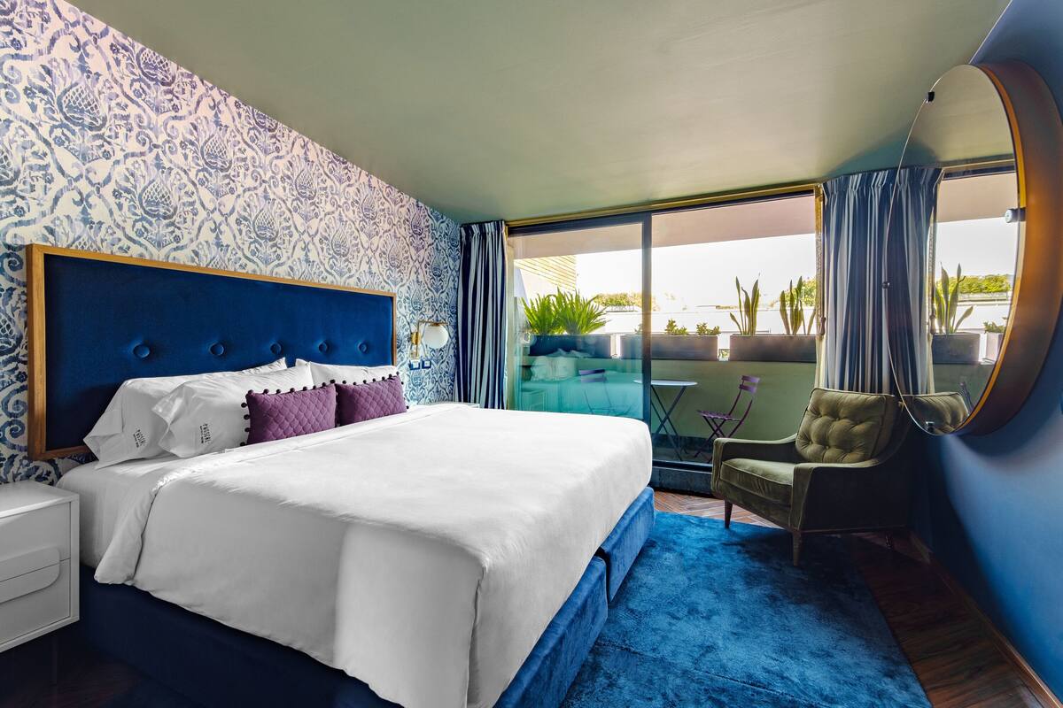 Une chambre d’hôtel avec un grand lit, une chaise, une petite table et une vue sur l’extérieur.