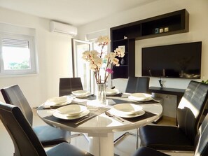A dining area with a round table set for four, surrounded by black leather chairs. A vase with white flowers is on the table. - Comfortable holiday house with apartments / Beautiful first floor apartment with terrace and grill / A3 (Pula)