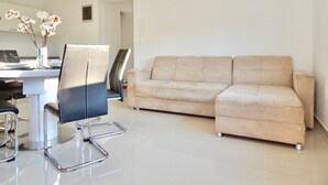 A modern living room with a beige sofa, a black office chair, a white table, and a vase with white flowers. - Comfortable holiday house with apartments / Beautiful first floor apartment with terrace and grill / A3 (Pula)