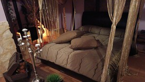 A bedroom with a four-poster bed, a bedside table with a lamp, and a small plant. - Typical house in finely furnished Sicilian style (Riposto)