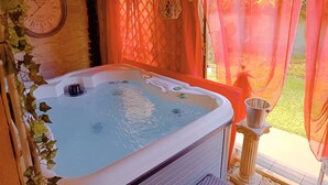 A hot tub with a clock on the wall, surrounded by greenery and orange curtains. - Typical house in finely furnished Sicilian style (Riposto)