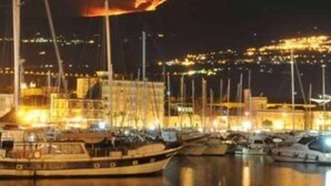 A marina at night with boats docked and a fire visible in the distance. - Typical house in finely furnished Sicilian style (Riposto)