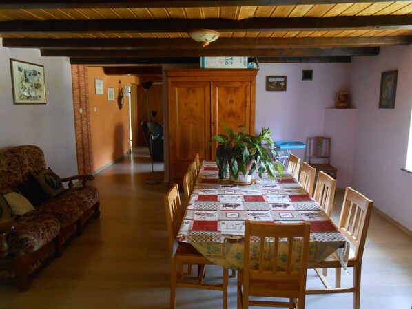 Un comedor con una mesa y sillas de madera, una planta en maceta y un sofá.
