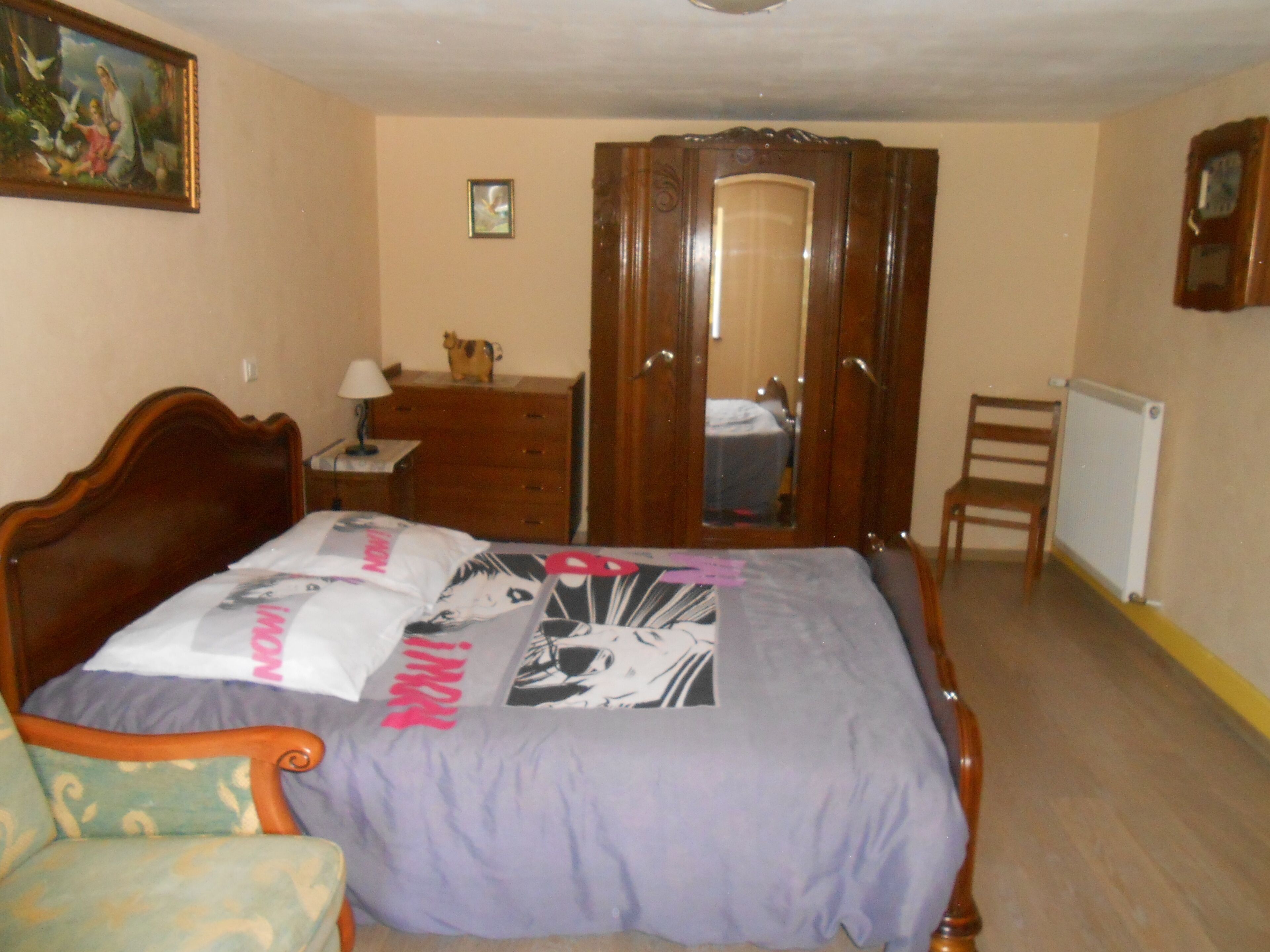 A bedroom with a wooden bed, a dresser, a chair, and a wardrobe.