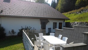 A house with a tiled roof, a patio with a table and chairs, and a wooden fence. - House / Villa - LA BRESSE (La Bresse)