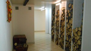 A hallway with tiled flooring, a wooden bench, and a wall with stacked firewood. - House / Villa - LA BRESSE (La Bresse)
