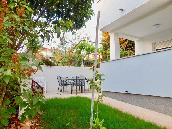 Enjoy dining or socializing in this outdoor patio area with a set of chairs and a table.