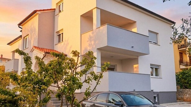 Un edificio moderno de dos pisos con un coche estacionado frente a él.