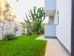 Stroll through a serene courtyard surrounded by lush greenery and a modern building with a flat roof.