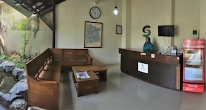 A reception area with a wooden reception desk, a clock, a map, a television, and a Coca-Cola refrigerator.
