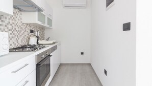 Eine kleine Küche mit weißen Schränken, einem Gaskochfeld, einem Toaster und einer Mikrowelle.