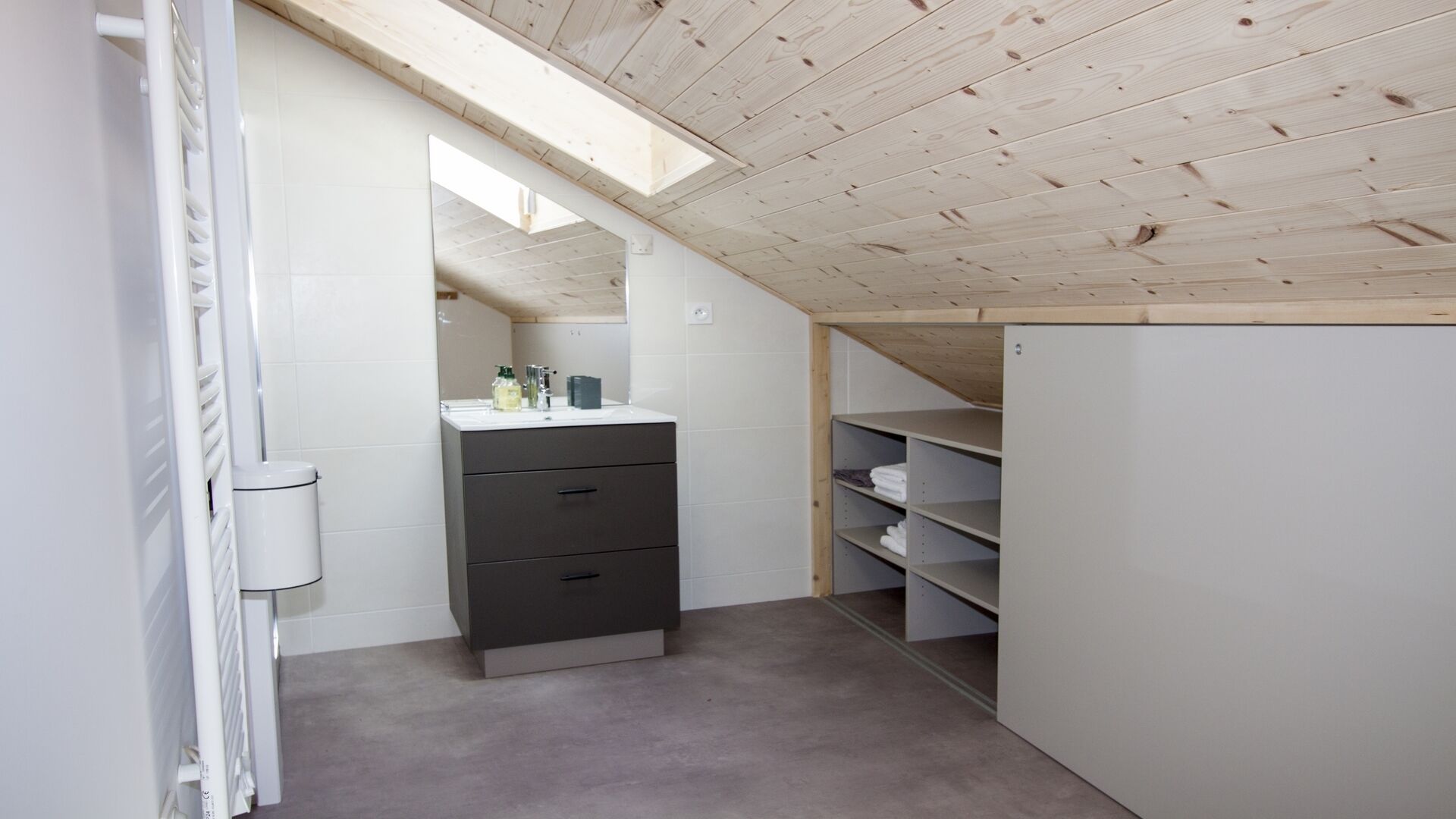 Un baño moderno y funcional con tragaluz, un mueble gris y un lavabo blanco.