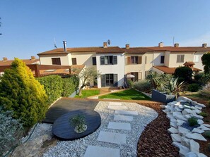 A modern two-story house with a well-maintained garden, a wooden deck, and a stone pathway. - Sea view modern spacious lounge house (Premantura)