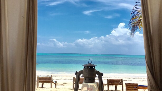 Vista da praia pela janela, com um candeeiro no parapeito.