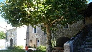 Un edificio de piedra con un árbol en primer plano, una escalera y una mesa de picnic.