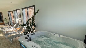 Ein Wellnessbereich mit Whirlpool, Liegestühlen und einer Holzterrasse.
