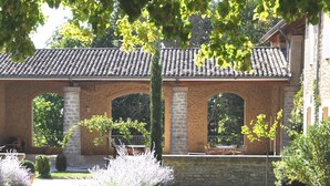 Ein Gebäude mit einem Ziegeldach, steinernen Bögen und einem Garten mit verschiedenen Pflanzen.