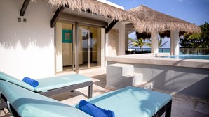 Un espace aménagé au bord de la piscine, avec des chaises longues et une structure dotée d’un toit de chaume.