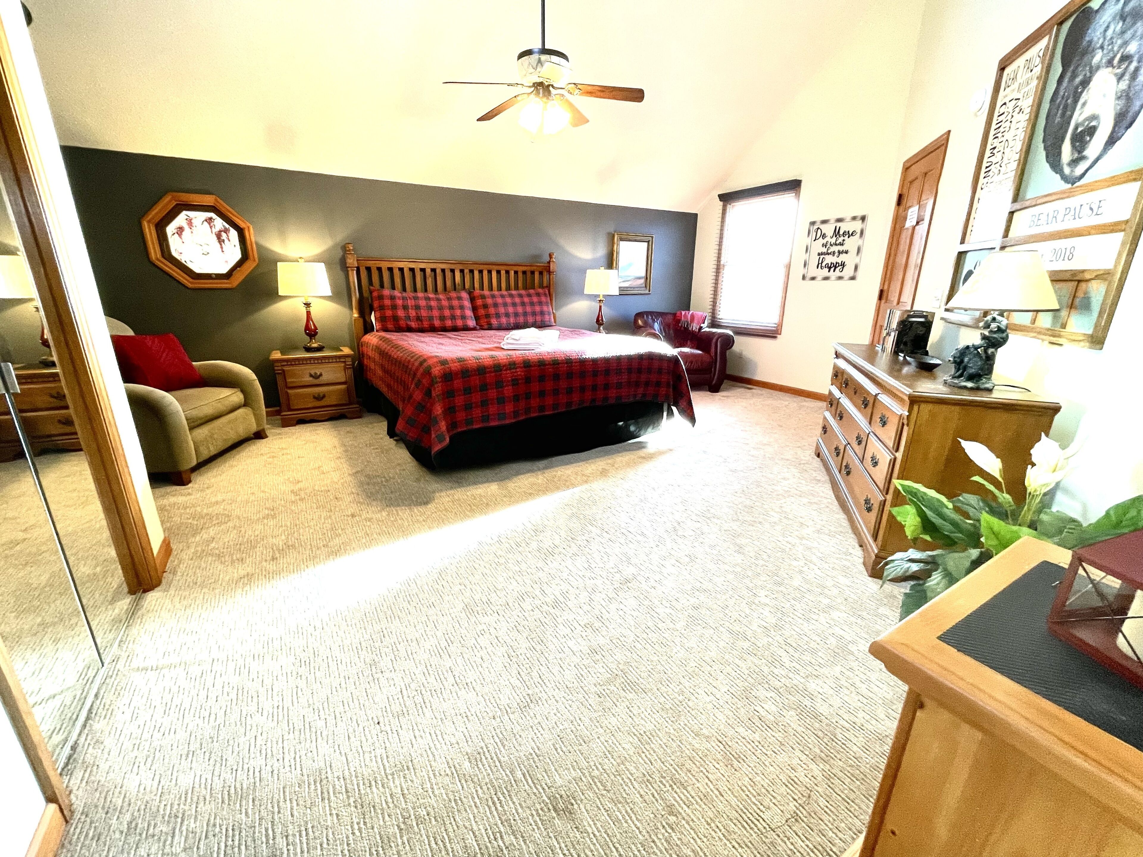 A bedroom with a bed, a chair, a dresser, and a ceiling fan.