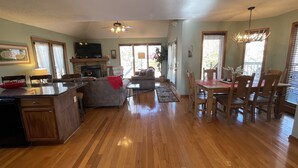A spacious living area with a fireplace, wooden flooring, a dining table with chairs, and a ceiling fan. - Bear Pause, a perfect family vacation home, minutes from attractions! (Pigeon Forge)