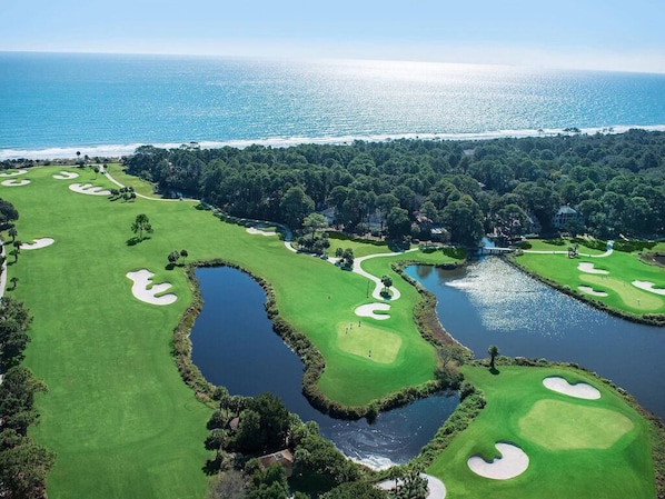 Eine Vogelperspektive auf einen Golfplatz mit mehreren Bunkern, Wasserhindernissen und einem Clubhaus.