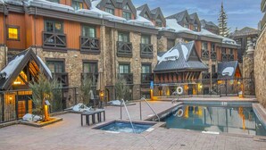 Un resort con piscina, mobiliario exterior y fachada de piedra.