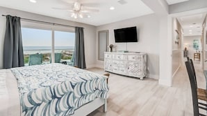 Une chambre avec un lit, une commode, une télévision et vue sur la plage.
