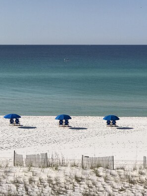 A beach with three blue umbrellas and beach chairs. - Amazing panoramic gulf views! Cleaning fees and beach service included! (Okaloosa Island)
