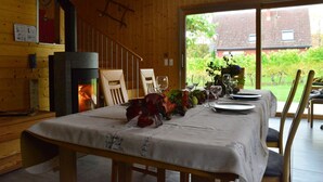A dining area with a table set for four, a fireplace, and a view of the garden. - Riesling cottage for 2 to 8 people, ideal for families,  (Rouffach)