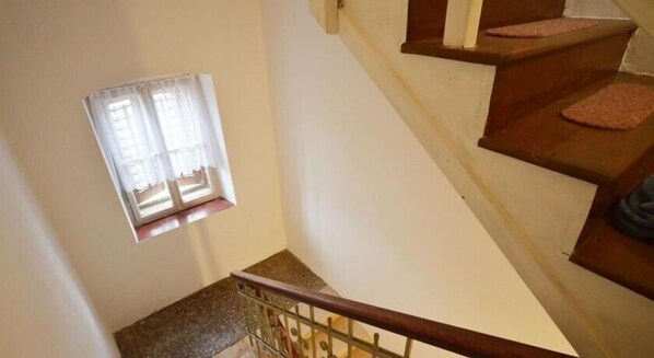 Eine Treppe mit Holzbodenstufen und einem Metallgeländer, die zu einer Zwischenebene mit einem Fenster führt.