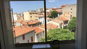 Una stanza con una grande finestra che si affaccia su una zona urbana densamente popolata con tetti in tegole rosse.