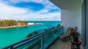 A balcony with a glass railing overlooking turquoise waters and a clear sky.