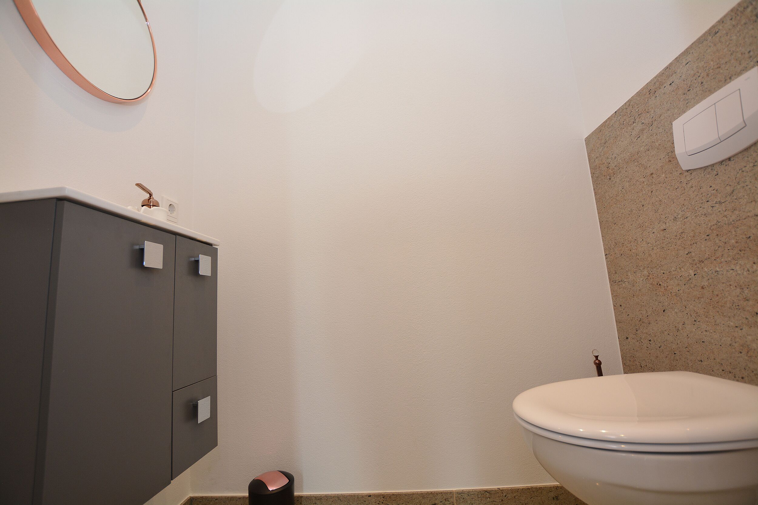A bathroom with a toilet, a sink, and a mirror.