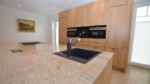 Eine moderne Küche mit Granitwerkplatten, Edelstahlgeräten und Holzschränken.