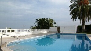 Una piscina con un deck blanco y una cerca blanca.