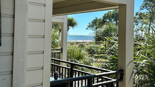 A covered outdoor area with a view of the ocean, surrounded by greenery and a railing. - Crashin' Waves-Oceanview w/new bikes, Chairs& King Bed (Hilton Head Island)