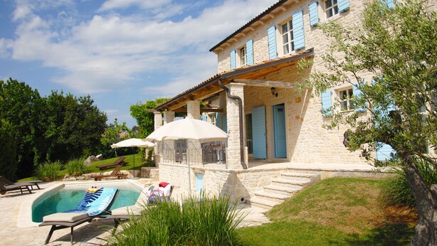 Ein Steinhäuschen mit Swimmingpool, Gartenmöbeln und einem gepflegten Garten.