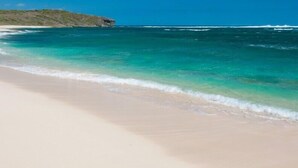 A beach with clear turquoise water and a sandy shore.
