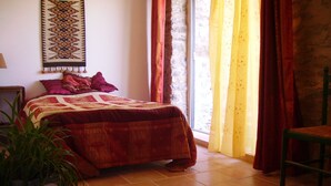 A bedroom with a bed, a chair, a potted plant, a wall hanging, and a window with curtains. - Cottage on the Cevennes foothills with exceptional views (Sumene)