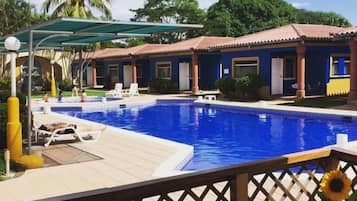 A swimming pool area with lounge chairs and a covered patio.
