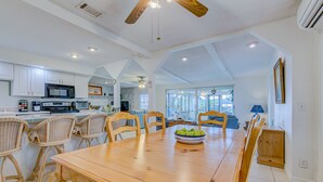 Une cuisine spacieuse avec des meubles blancs, un four à micro-ondes et un coin repas comprenant une table en bois et des chaises en osier.