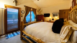 Une chambre à coucher avec un cadre de lit en bois, un ventilateur de plafond et des décorations en forme de bois de cerf.