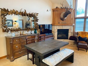 A living room with a fireplace, a large mirror, and a deer head mounted above it.