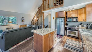 A modern kitchen with wooden cabinets, a stainless steel refrigerator, and a built-in oven.