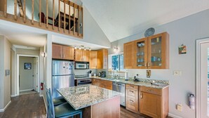 A modern kitchen with wooden cabinets, granite countertops, a stainless steel refrigerator, and a built-in microwave.