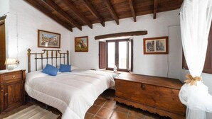 Une chambre à coucher avec un lit en bois, une table de chevet, une commode et une fenêtre avec des rideaux.